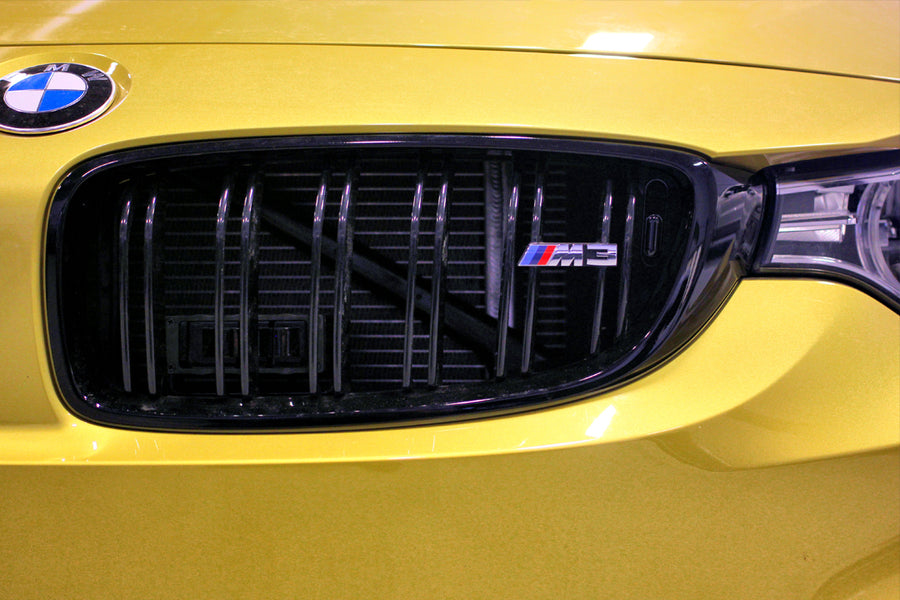 Close-up of yellow BMW M3 front grille with emblem badge